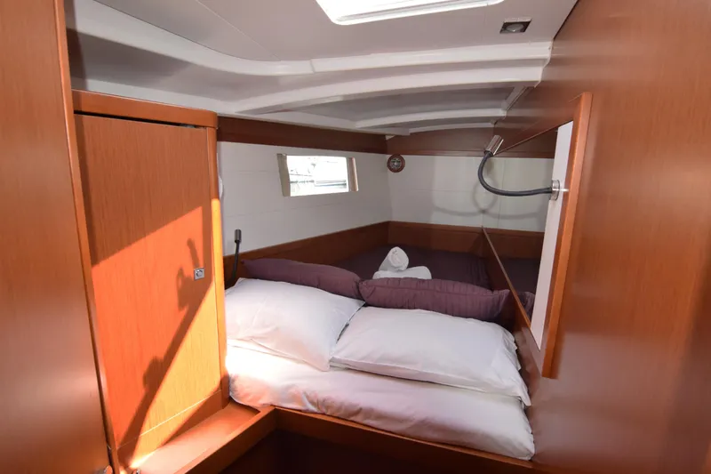  Yacht Photos Pics Cozy cabin interior of 2015 Beneteau Oceanis 48 yacht with wooden finish and comfortable bedding.