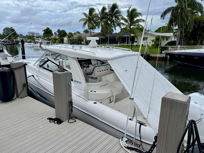  Yacht Photos Pics 2023 Intrepid 438 Evolution yacht docked by a scenic waterfront with palm trees.