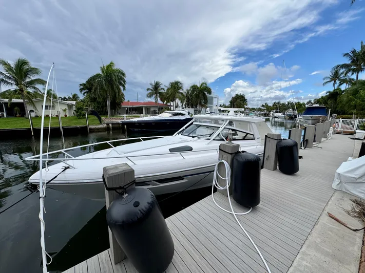  Yacht Photos Pics 2023 Intrepid 438 Evolution yacht docked by palm trees under a cloudy sky.