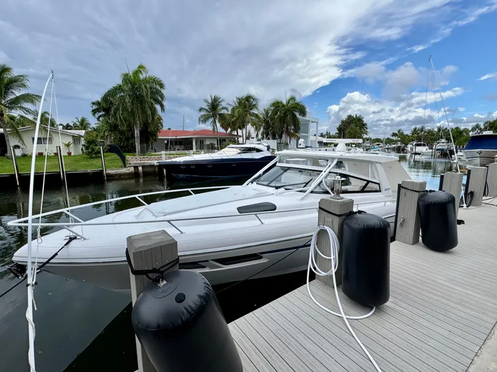  Yacht Photos Pics 2023 Intrepid 438 Evolution yacht docked by palm trees under a cloudy sky.
