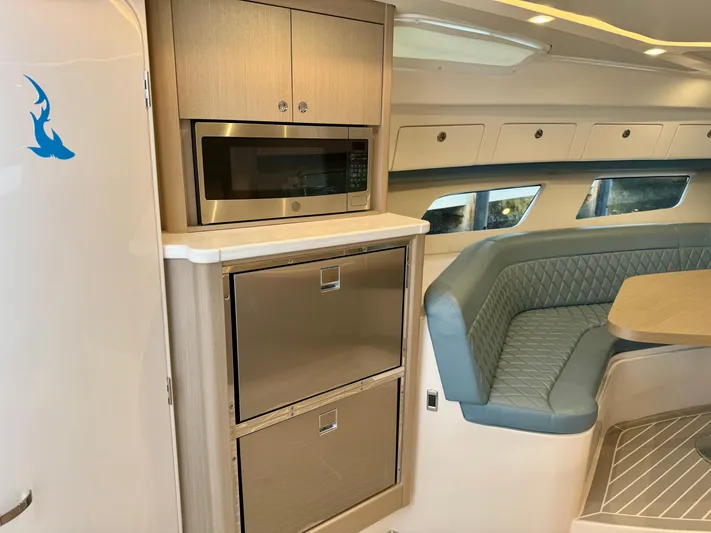  Yacht Photos Pics 2023 Intrepid 438 Evolution interior with microwave, storage, and cushioned seating area.