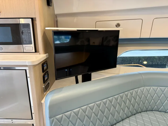  Yacht Photos Pics 2023 Intrepid 438 Evolution interior with TV, microwave, and quilted seating.