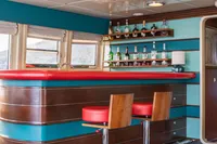 Luxurious bar area on 1986 Motor Yacht 38m Nicolini with vibrant red and teal decor.