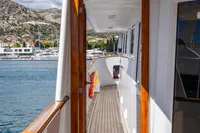 Side deck view of 1986 Motor Yacht 38m Nicolini, featuring wooden railings and scenic waterfront.