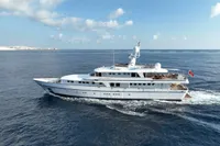 38m Nicolini motor yacht cruising on open sea, 1986 model, under clear blue sky.