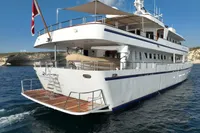 38m Nicolini motor yacht, 1986 model, cruising in clear blue waters with a Danish flag.