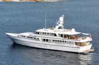 38m Nicolini motor yacht from 1986 on calm sea near rocky shore.