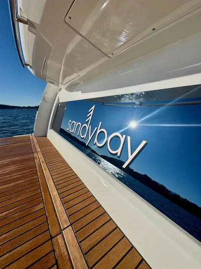Sandybay Yacht Photos Pics Prestige 520 Fly 2022 yacht with "sandy bay" logo, wooden deck, and ocean view.