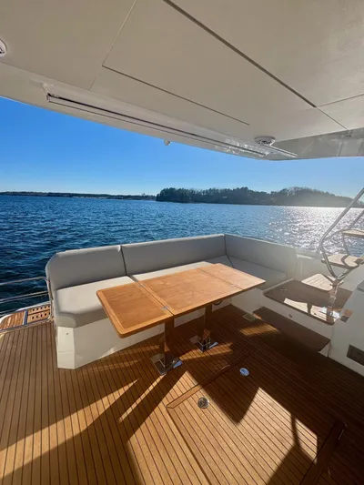 Sandybay Yacht Photos Pics Prestige 520 Fly 2022 yacht deck with seating and table, overlooking serene water.