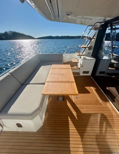 Sandybay Yacht Photos Pics Luxurious 2022 Prestige 520 Fly yacht deck with seating and table, overlooking serene water.