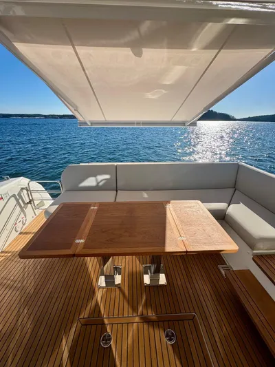 Sandybay Yacht Photos Pics Luxury yacht deck with wooden table, Prestige 520 Fly 2022, overlooking serene ocean view.
