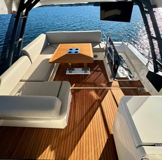 Sandybay Yacht Photos Pics Prestige 520 Fly 2022 yacht deck with seating and table, overlooking serene water.