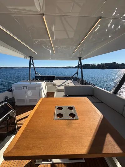 Sandybay Yacht Photos Pics Prestige 520 Fly 2022 yacht deck with wooden table, overlooking serene water.