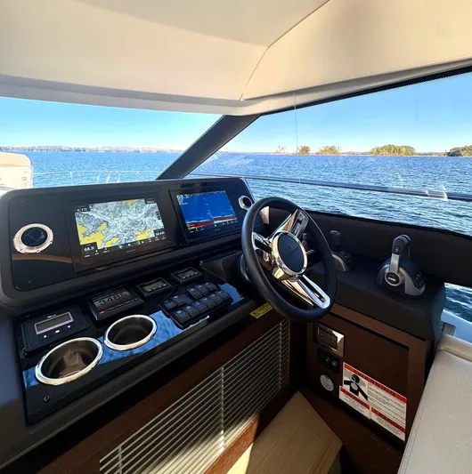 Sandybay Yacht Photos Pics 2022 Prestige 520 Fly yacht helm with navigation screens and steering wheel, overlooking serene waters.