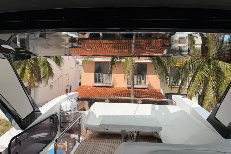 Atkun Yacht Photos Pics Sunseeker Manhattan 68 yacht deck with covered seating, palm trees, and building view.