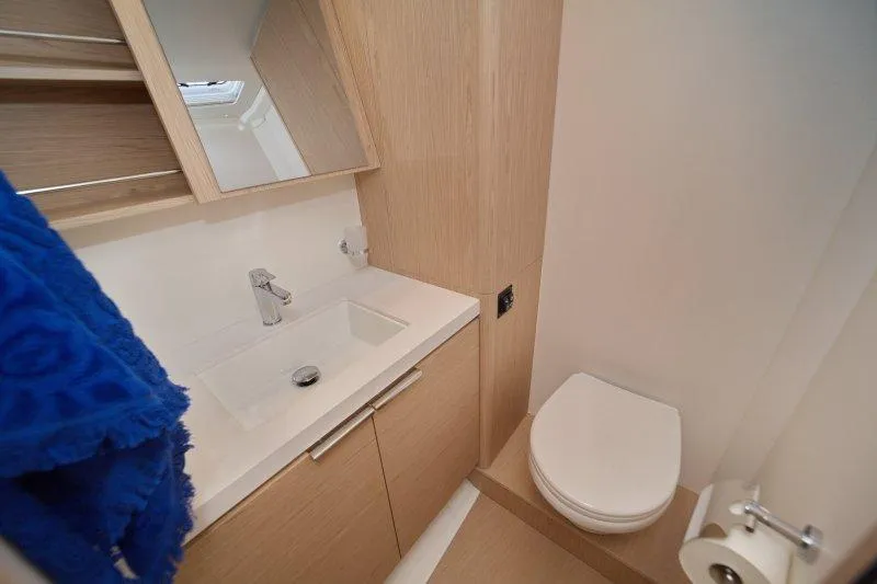  Yacht Photos Pics Modern bathroom in 2022 Beneteau Oceanis Yacht 54, featuring sleek sink and toilet.