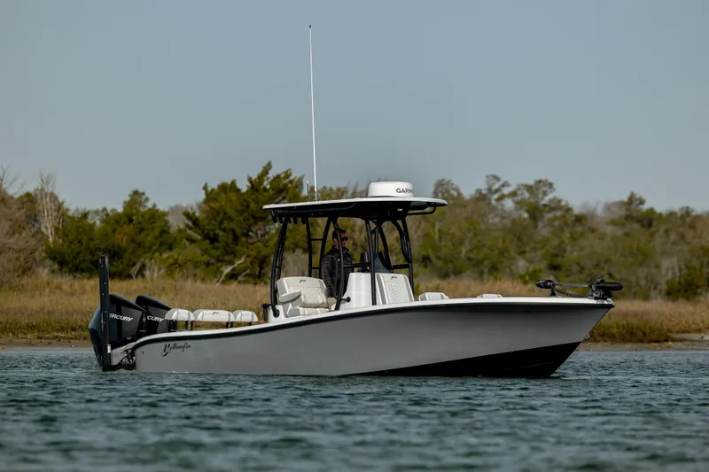  Yacht Photos Pics 2025 Yellowfin 26 Hybrid boat on calm water, surrounded by lush greenery.