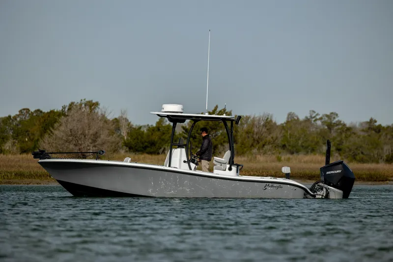  Yacht Photos Pics 2025 Yellowfin 26 Hybrid boat on water, side view with trees in background.