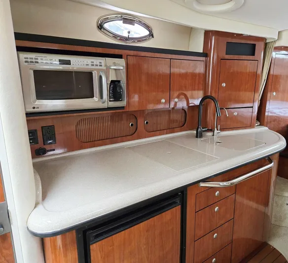 O Sea D Yacht Photos Pics 2007 Sea Ray 340 Sundancer kitchen with microwave, sink, and wooden cabinetry.