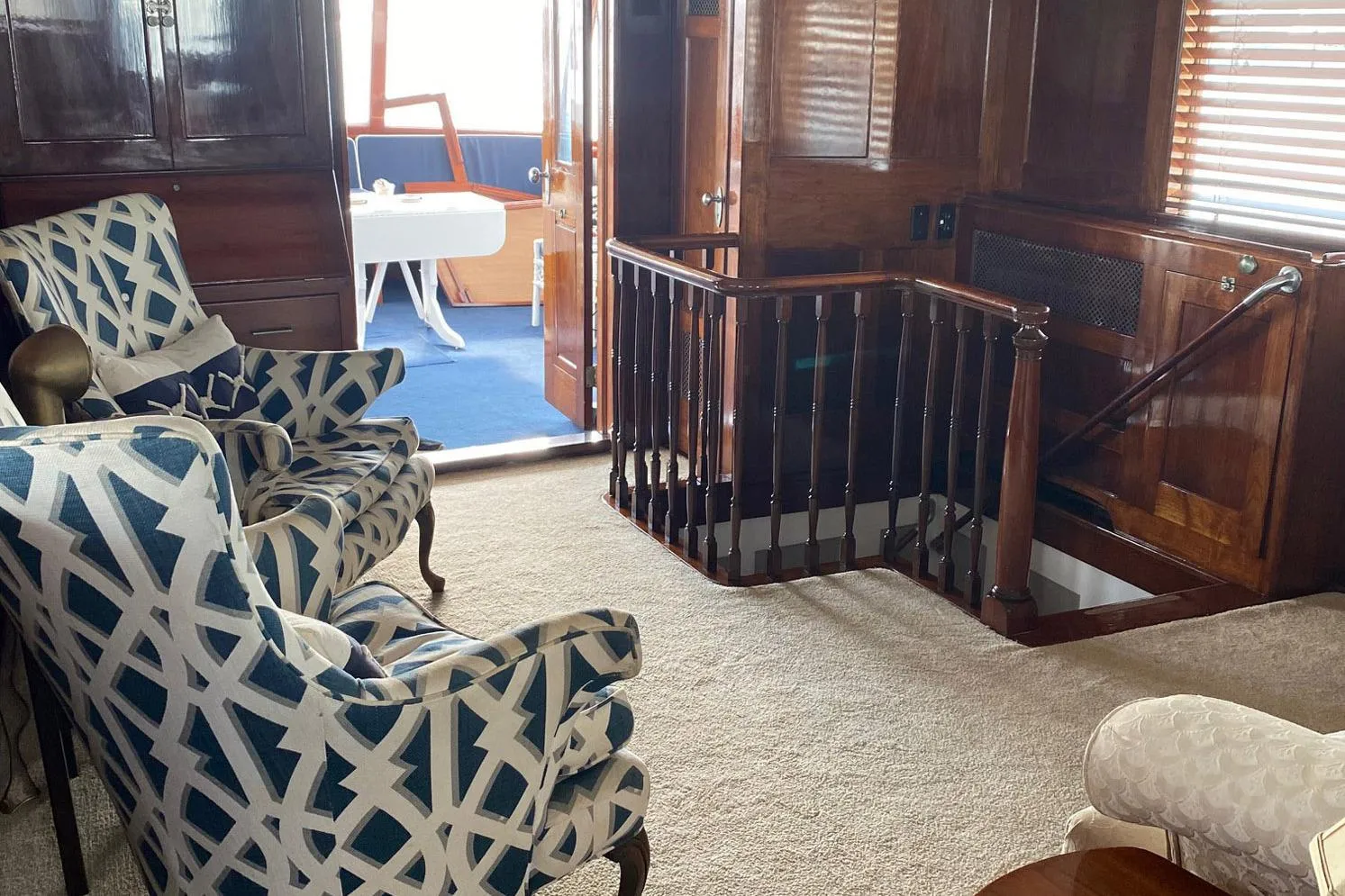 Interior of 1954 Trumpy 68 Motor Yacht with patterned chairs and wooden finishes.