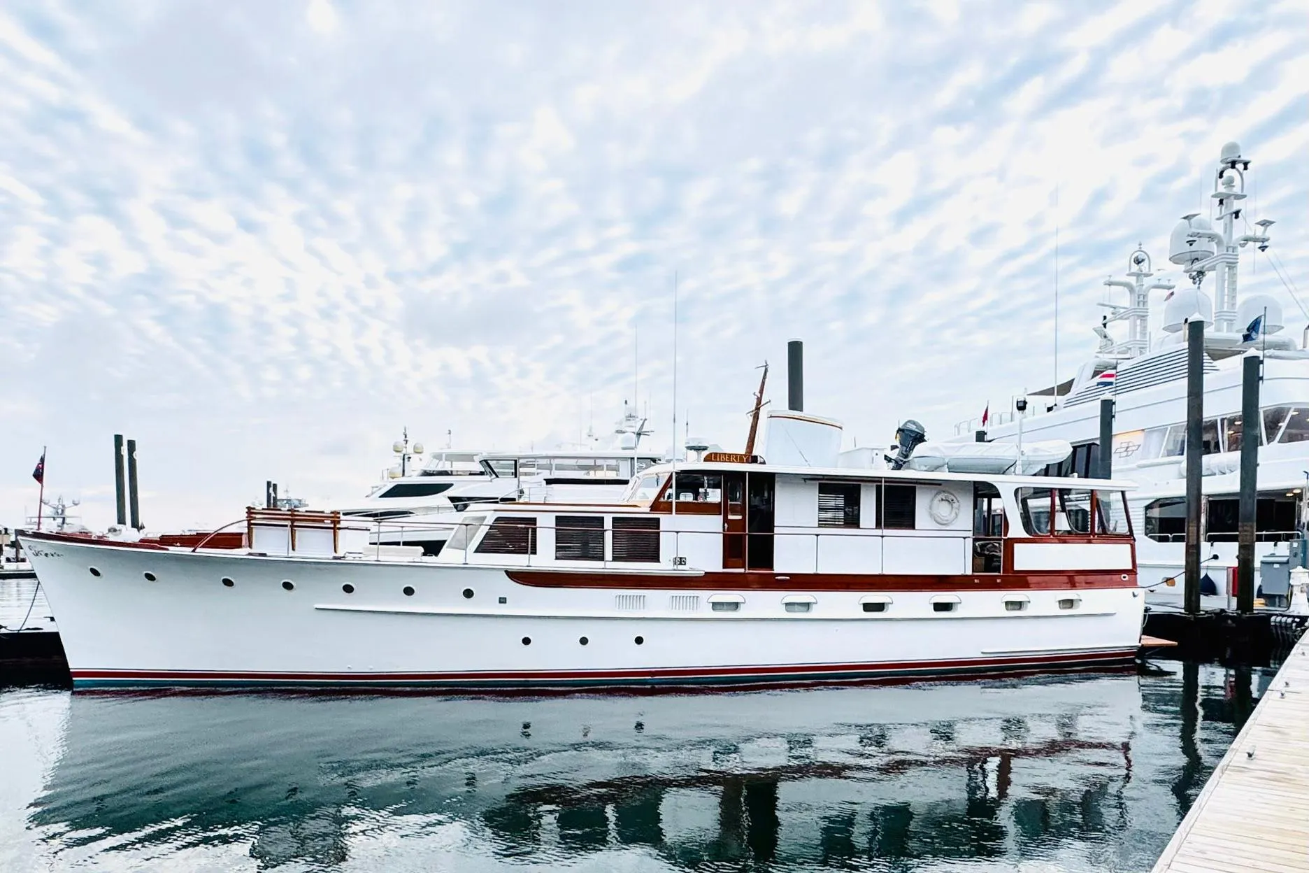 Classic 1954 Trumpy 68 Motor Yacht docked at marina under cloudy sky.
