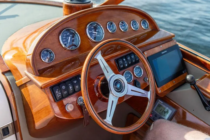 Fiveadrift Yacht Photos Pics Steering wheel and dashboard of a 2003 Hinckley Talaria 29R boat, featuring wood finish and gauges.