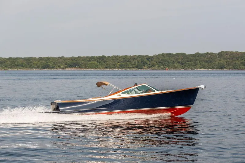 Fiveadrift Yacht Photos Pics 2003 Hinckley Talaria 29R cruising on calm waters near a forested shoreline.
