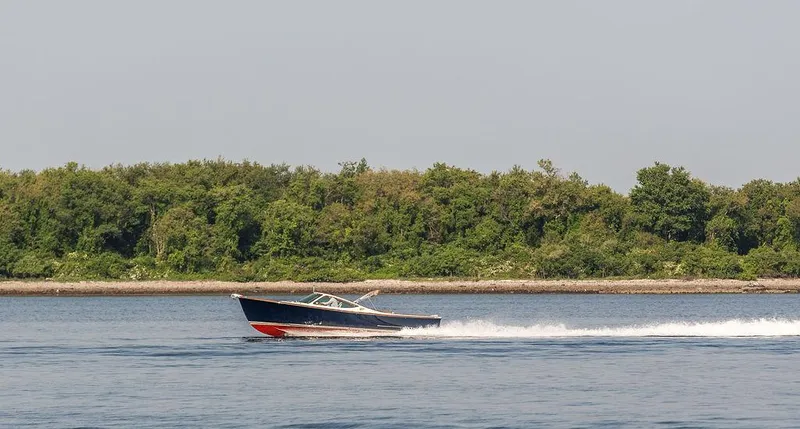 Fiveadrift Yacht Photos Pics 2003 Hinckley Talaria 29R cruising on water near a lush green shoreline.