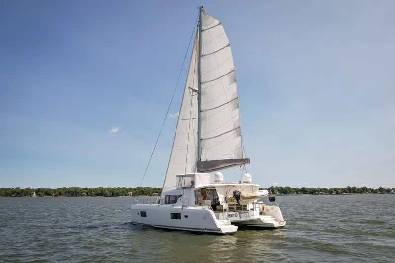 Reunited Yacht Photos Pics 2017 Lagoon 42 catamaran sailing on a calm lake under clear blue skies.