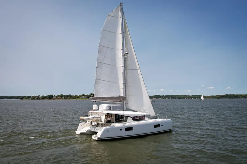 Reunited Yacht Photos Pics 2017 Lagoon 42 catamaran sailing on a calm lake under clear blue skies.