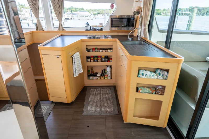 Reunited Yacht Photos Pics Modern kitchen interior on a 2017 Lagoon 42 catamaran, featuring wooden cabinetry and ample storage.