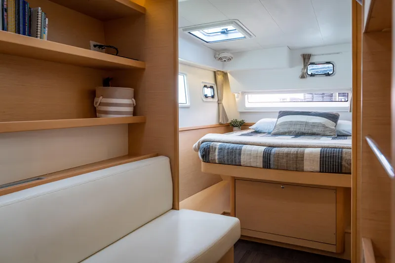 Reunited Yacht Photos Pics Luxurious interior of 2017 Lagoon 42 catamaran with cozy bed and wooden shelves.