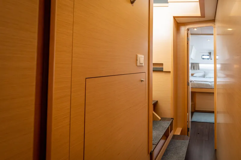 Reunited Yacht Photos Pics Interior hallway of 2017 Lagoon 42 yacht, featuring wooden paneling and a cozy bedroom.
