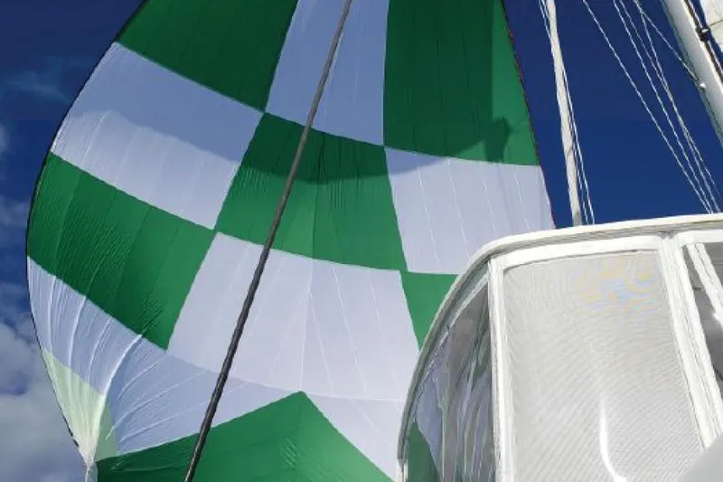 Reunited Yacht Photos Pics Green and white sail on a 2017 Lagoon 42 catamaran against a clear blue sky.