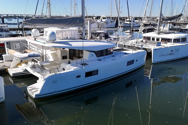 Reunited Yacht Photos Pics 2017 Lagoon 42 catamaran docked in a marina, surrounded by other boats.