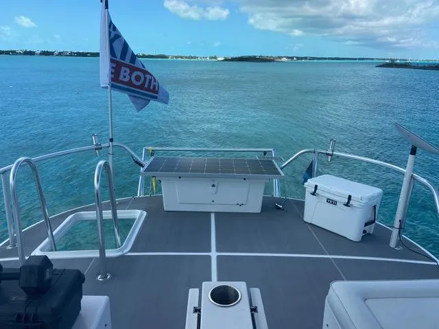 Korkzcrew Yacht Photos Pics Great Harbour N37 boat deck with solar panel, cooler, and flag on calm blue water.