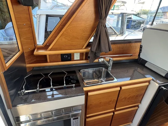  Yacht Photos Pics 2016 Cutwater C-28 boat kitchen with stove, sink, and wooden cabinetry.