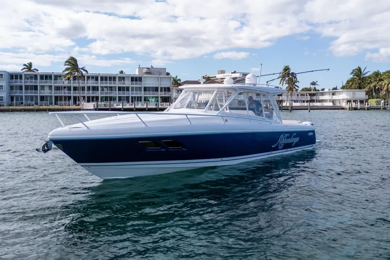  Yacht Photos Pics 2019 Intrepid 407 Cuddy boat on water near waterfront buildings and palm trees.