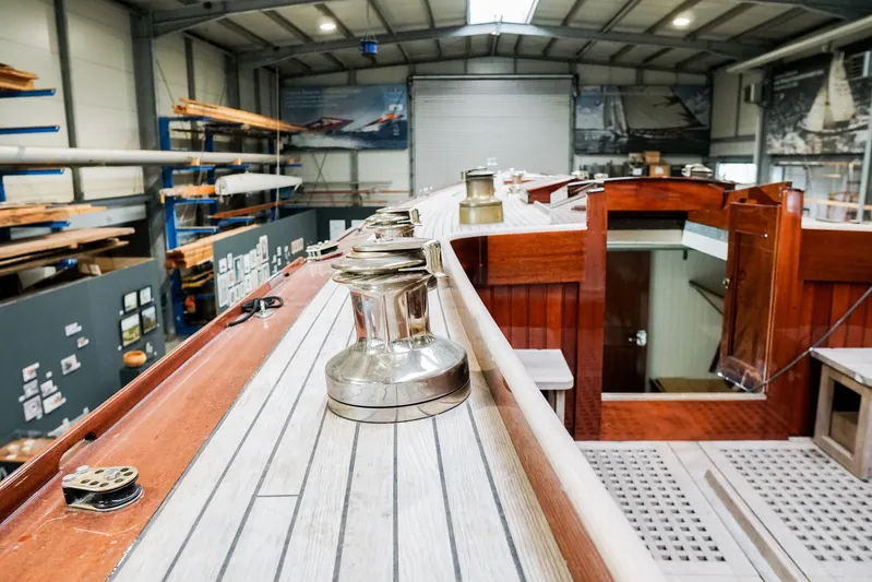 Wings K-15 Yacht Photos Pics Restored 1937 Classic 12-metre yacht interior with wooden deck and polished fittings in a workshop.