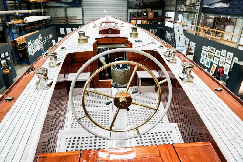 Wings K-15 Yacht Photos Pics Interior view of a restored 1937 Classic 12-metre yacht with wooden deck and steering wheel.