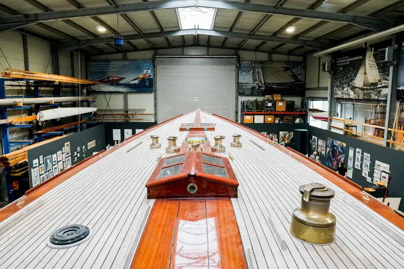Wings K-15 Yacht Photos Pics Restored 1937 Classic 12-metre yacht in a workshop, showcasing detailed wooden deck craftsmanship.