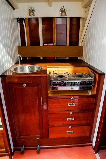 Wings K-15 Yacht Photos Pics Vintage 1937 Classic 12-metre yacht kitchen with wooden cabinetry, sink, and stove.