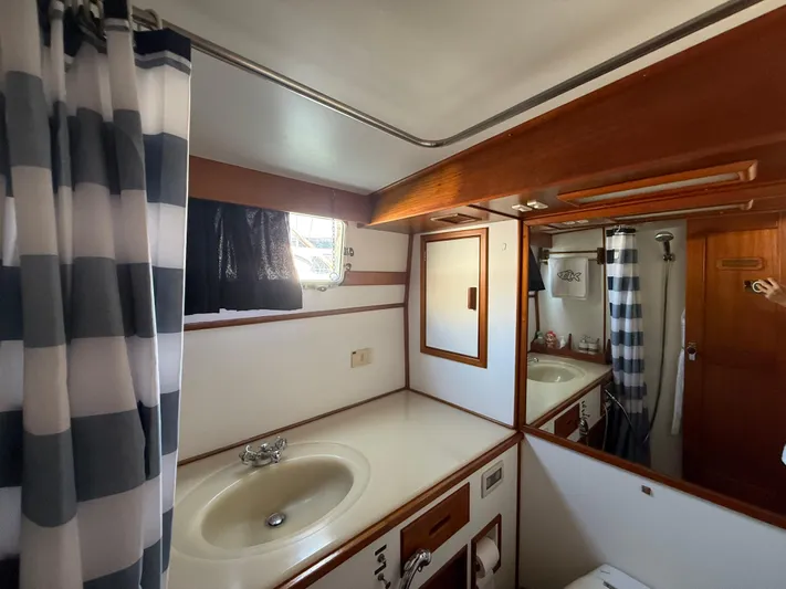 Aramis II Yacht Photos Pics Bathroom interior of 1990 Grand Banks 49 yacht with sink, mirror, and shower curtain.