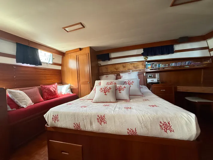 Aramis II Yacht Photos Pics Luxurious 1990 Grand Banks 49 yacht bedroom with elegant wood paneling and coral-themed bedding.