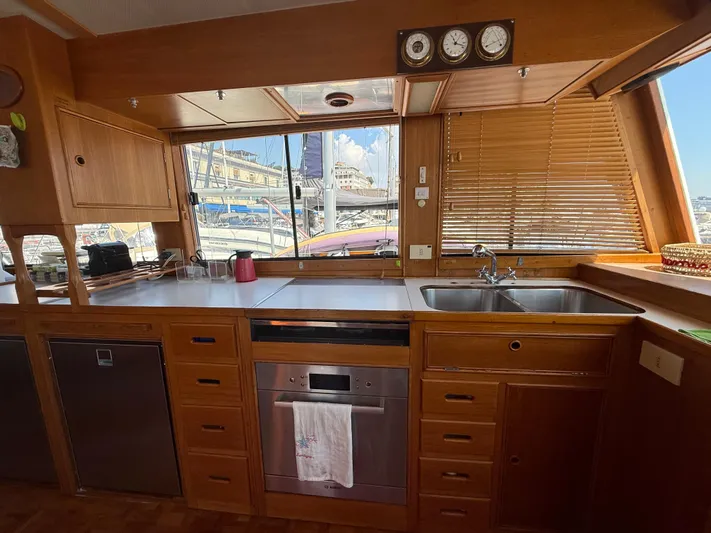 Aramis II Yacht Photos Pics Interior of 1990 Grand Banks 49 yacht kitchen with wooden cabinetry and marina view.
