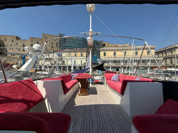 Aramis II Yacht Photos Pics Luxurious 1990 Grand Banks 49 yacht deck with red seating, docked in a scenic marina.