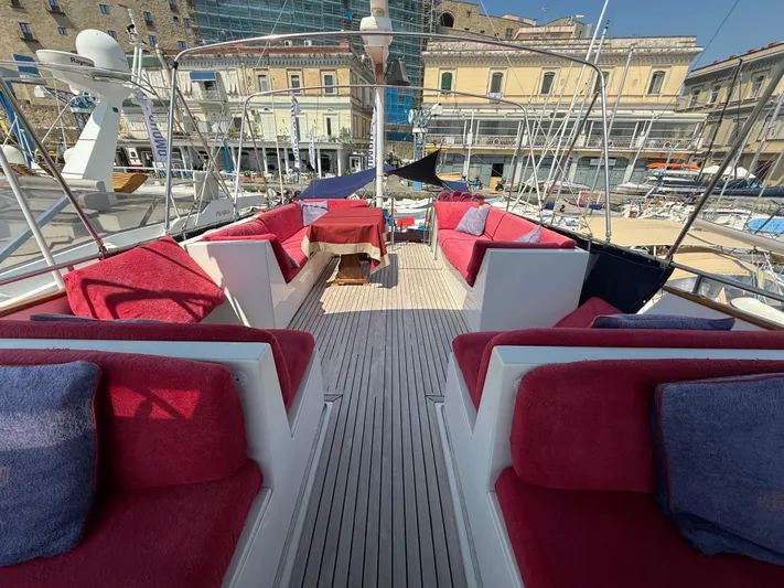 Aramis II Yacht Photos Pics Luxurious 1990 Grand Banks 49 yacht deck with red seating and cityscape background.