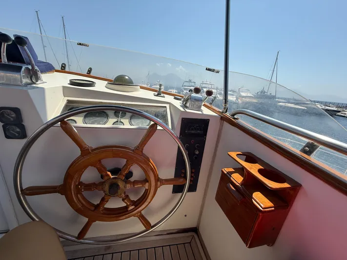Aramis II Yacht Photos Pics Helm of 1990 Grand Banks 49 yacht with wooden wheel and marina view.