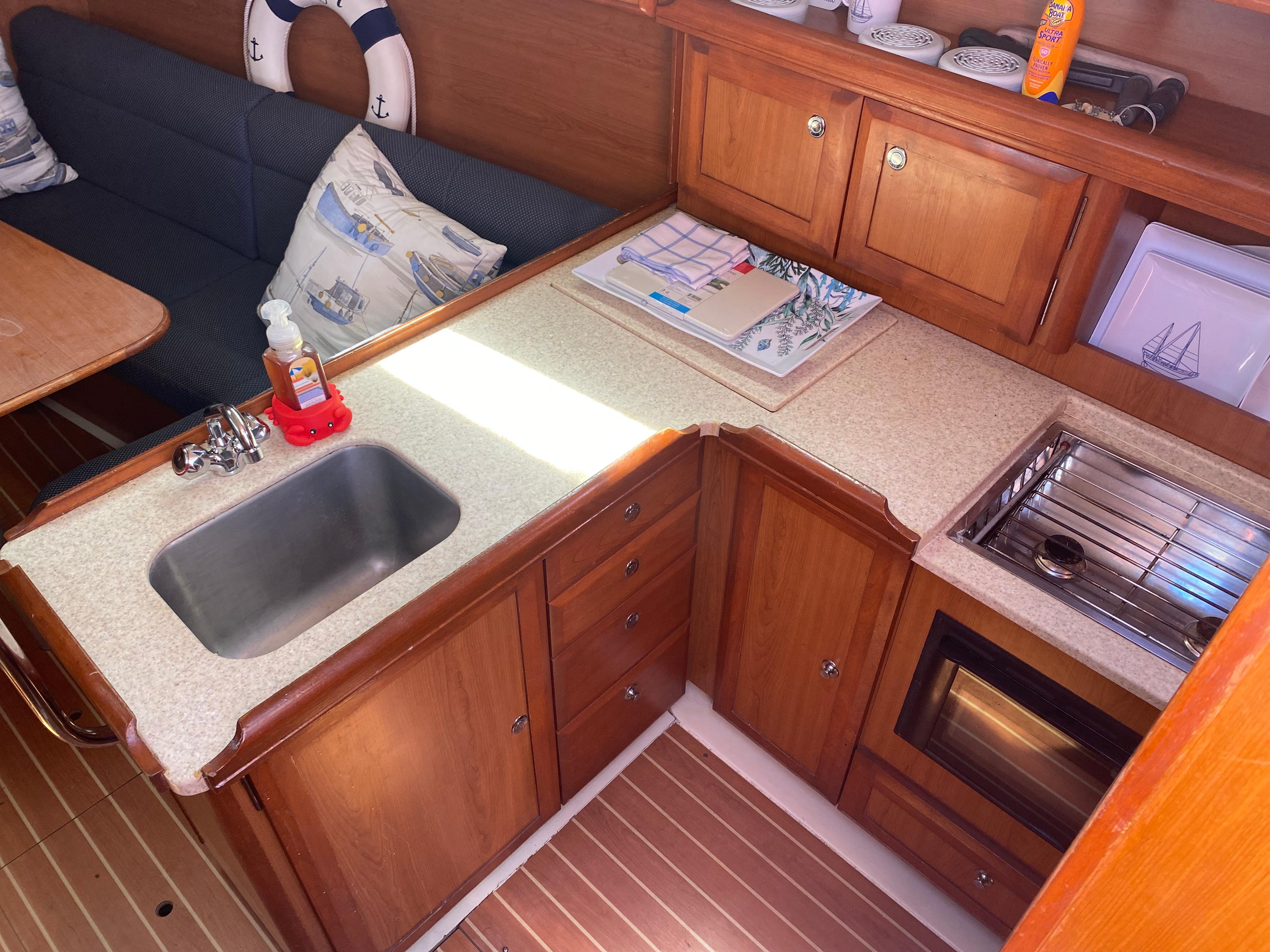 2009 Hunter 31-2 sailboat kitchen with sink, stove, and wooden cabinetry.