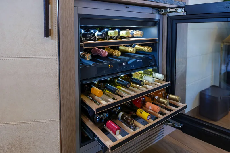 Heliophilia Yacht Photos Pics Wine cooler with wooden shelves in a 2024 Sirena 88 yacht interior.